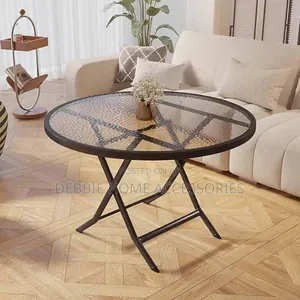Round Folding Table With a Tempered Glass Top and a Black Metal Frame.